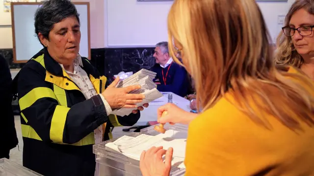 Una trabajadora de Correos entrega en una mesa de Vizcaya los votos emitidos por correo
