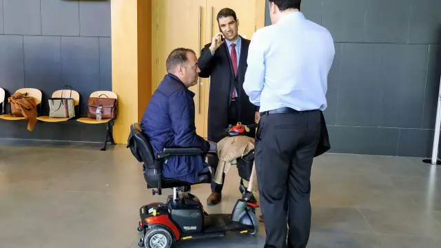 El demantante, en silla de ruedas, junto a su abogado, Víctor Laguardia, hablando por teléfono.