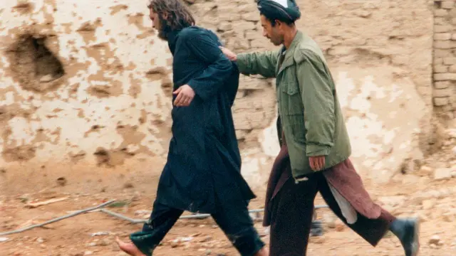 FILE PHOTO: U.S.-born John Walker Lindh (L) is led away by a Northern Alliance soldier after he was captured among al Qaeda and Taliban prisoners following an uprising at the Fort Qali-i-Janghi prison near Mazar-i-Sharif December 1, 2001 REUTERS/STR/File Photo [[[REUTERS VOCENTO]]] USA-CRIME/LINDH