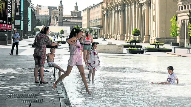 Varias personas se refrescan para combatir el calor, este martes en la fuente de Goya de Zaragoza.