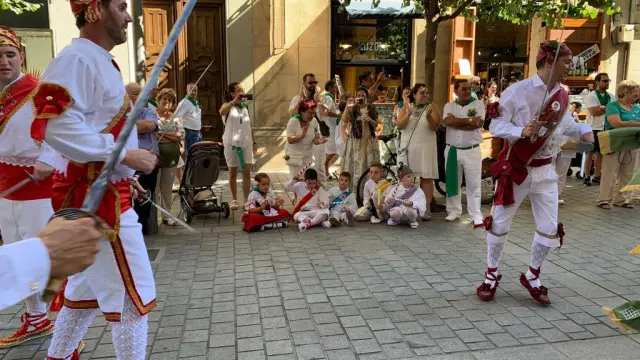 Vocación de danzante: unos niños vestidos como los miembros de la agrupación los jalean con los palos a su paso por el Coso.
