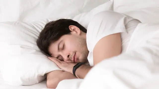 Un adulto duerme plácidamente en su cama.