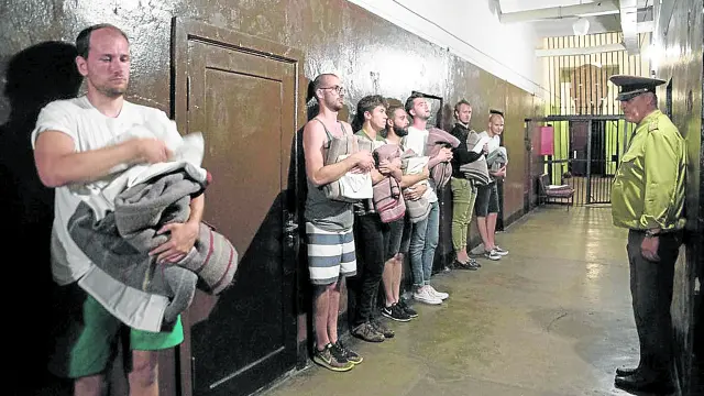 Unos turistas que se han atrevido a pasar la noche como reos son inspeccionados en la cárcel de Karosta por el oficial de turno.