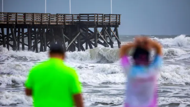 Unas personas contemplan la marea en la playa de Daytona, Florida, antes de la llegada del huracán Dorian.