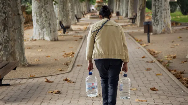 Una mujer camina por Daroca con dos garrafas de agua.