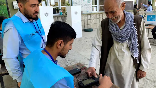 Un afgano que acude a votar intenta sin éxito que la máquina biométrica registre sus huellas dactilare