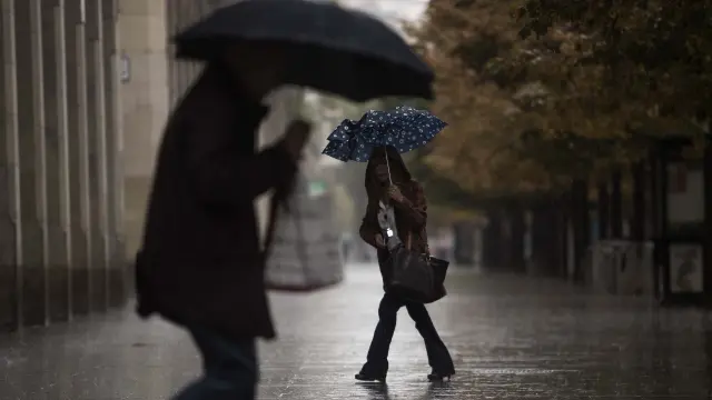 Dos personas se protegen de la lluvia en Zaragoza