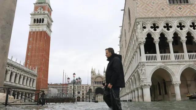 Un hombre camina por una inundada calle de Venecia.