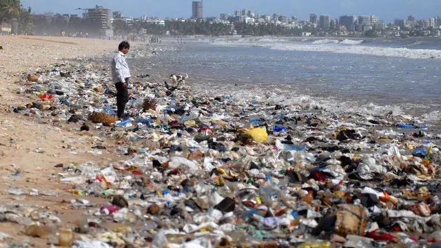 Un hombre observa una montaña de plásticos a orillas del mar Arábigo en Bombay (La India).