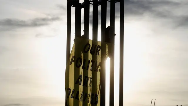 Activistas de Greenpeace despliegan una pancarta en una torre de iluminación del recinto ferial Ifema.