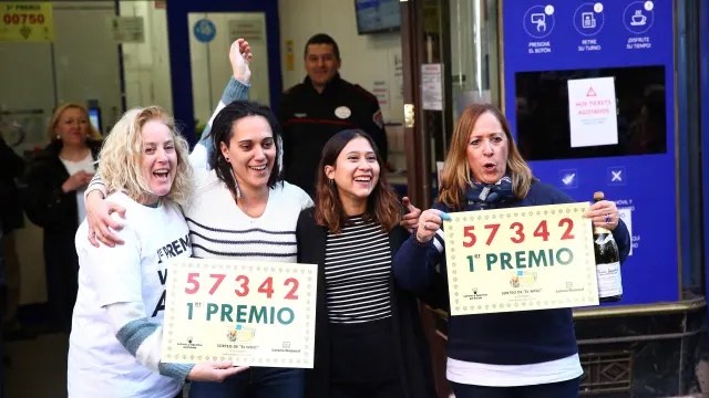 Un grupo de personas celebra en la administración de Lotería Doña Manolita haber dado parte del primer premio del sorteo.