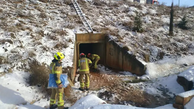 Los bomberos de la DPT actuando para evitar un vertido de gasóleo tras el accidente de un camión en la Vía Perimetral de Teruel a causa de la nieve.