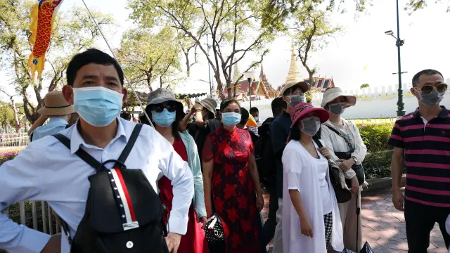 Turistas chinos llevan mascarillas durante la visita al Gran Palacio en Bangkok (Tailandia)