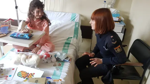 Una policía nacional charla con una niña hospitalizada