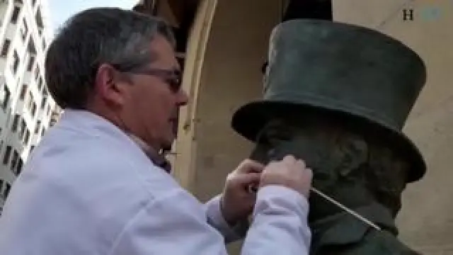 Dos técnicos de la unidad de restauración del Ayuntamiento de Zaragoza realizan labores de limpieza en el busto de Felipe Sanclemente situado en el paseo de la Independencia