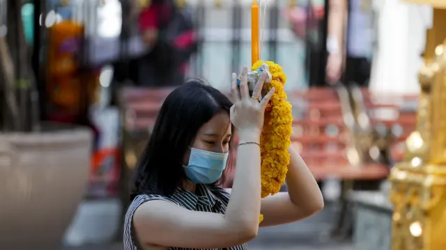 Una mujer reza con una mascarilla de protección en un templo hindú en Bangkok (Tailandia).