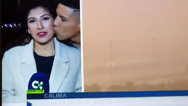 Momento en el que la periodista un besada por un viandante mientras hace un directo sobre la situación del aeropuerto de Lanzarote por la calima