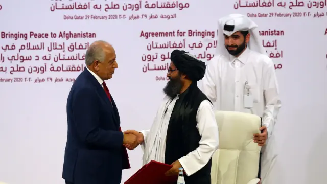 El mulá Abdul Ghani Baradar y Zalmay Khalilzad se estrechan la mano tras la firma del acuerdo.