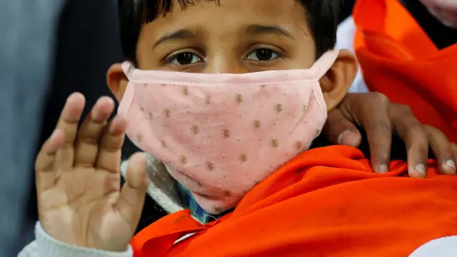 A boy wears a mask as he waits for the start of the first One-day International cricket match between India and South Africa, amid coronavirus fears, in Dharamsala