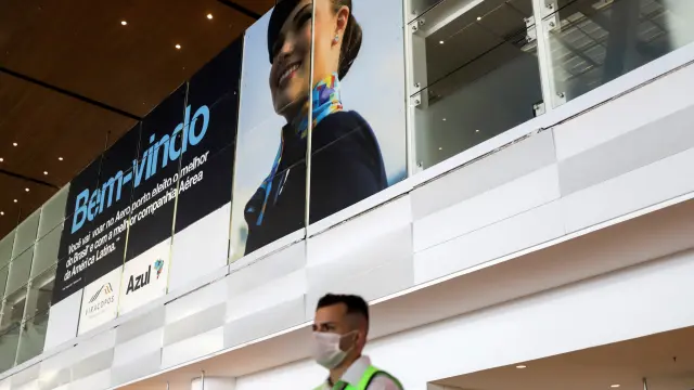 Man wearing a face mask stands under a Brazilian airline Azul welcome banner, after the airline stated it will cut all of its international flights out of its main hub due to the coronavirus outbreak, at Viracopos International Airport, in Campina