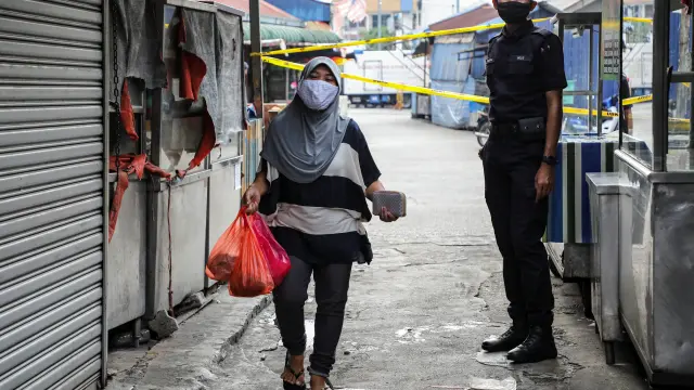 A police officer stands guard at an entrance of a market, during the movement control order due to the outbreak of the coronavirus disease (COVID-19), in Kuala Lumpur