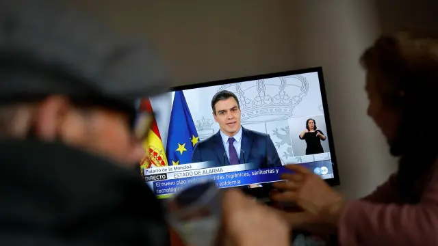 An elderly couple eats lunch at their home as they watch Spanish Prime Minister Pedro Sanchez on a television screen during a live news conference, due to the coronavirus disease (COVID-19) outbreak, in Ronda, southern Spain April 4, 2020. REUTERS/Jon Nazca [[[REUTERS VOCENTO]]] HEALTH-CORONAVIRUS/SPAIN