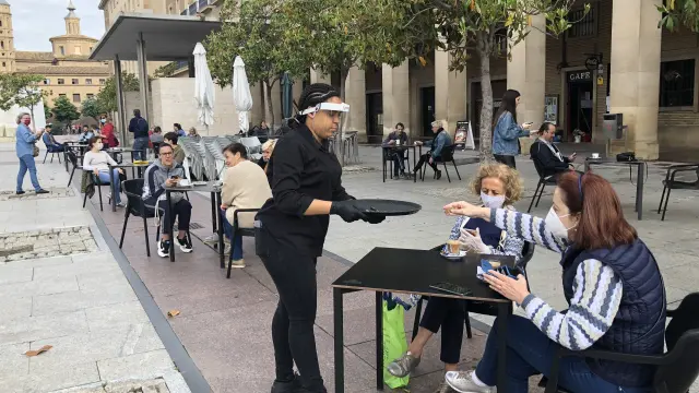 Una camarera sirve y cobra una consumición en la Plaza del Pilar