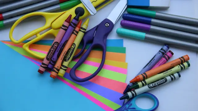 Tijeras, papel y lápices de colores para hacer la manualidad.