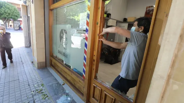Un cristalero coloca una nueva luna en la puerta de la peluquería donde han robado.