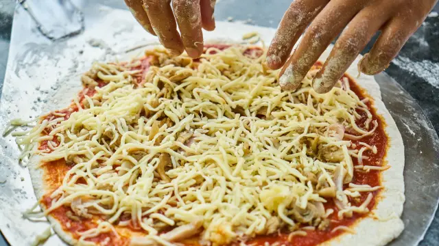 Una pizza casera puede propiciar buenos ratos en familia aprendiendo a cocinar.