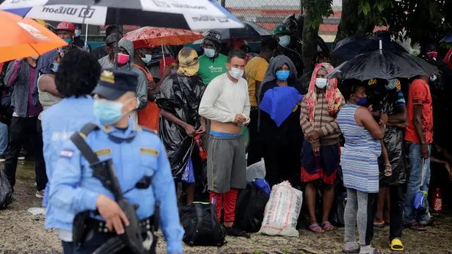 Stranded migrants from Africa, Cuba and Haiti shield from the rain in Tegucigalpa