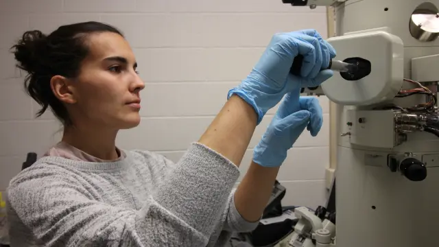 Irene Andreu, insertando una muestra en un microscopio electrónico de transmisión, en la Universidad de Rhode Island.