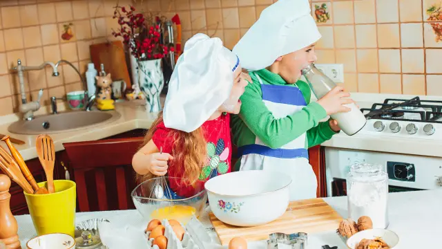 The happy two funny kids are preparing the dough, bake cookies in the kitchen