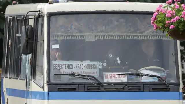 Ukrainian law enforcement officers lie on the ground behind a car near a passenger bus, which was seized by an unidentified person in the city of Lutsk, Ukraine July 21, 2020. REUTERS/Tetiana Hrishyna [[[REUTERS VOCENTO]]] UKRAINE-HOSTAGES/