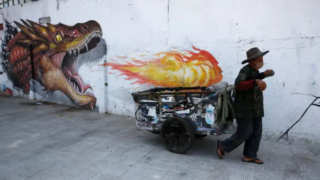 Un hombre se protege con mascarilla ante un mural sobre el coronavirus en Jakarta