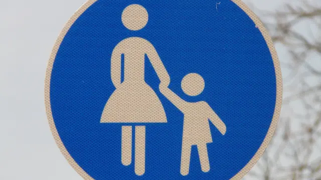 Una señal con la imagen de un niño de la mano de una mujer.