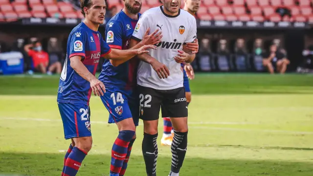 Seoane y Pulido, de la SD Huesca, junto a Maxi Gómez, del Valencia.