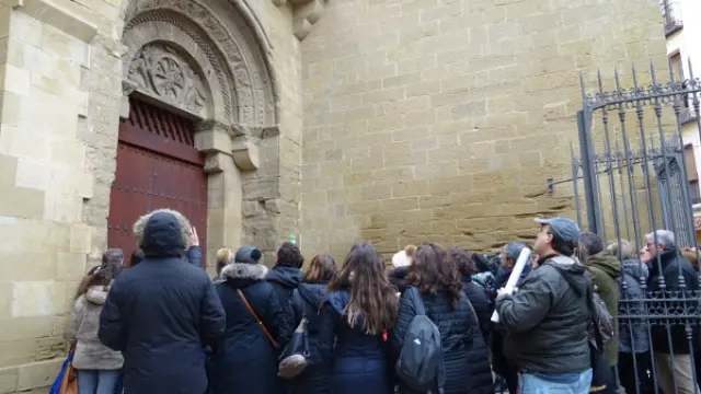 Un grupo de turistas en la entrada de la iglesia de San Pedro, incluida en la visita guiada a Huesca.