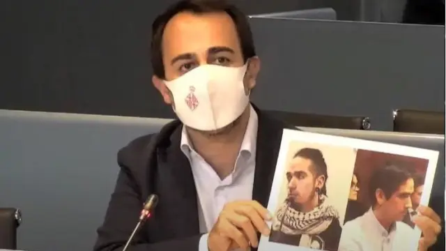 Óscar Ramírez, concejal del PP, muestra dos fotos de Rodrigo Lanza al realizar su propuesta de retirar el premio Ciudad de Barcelona al documental sobre su historia.