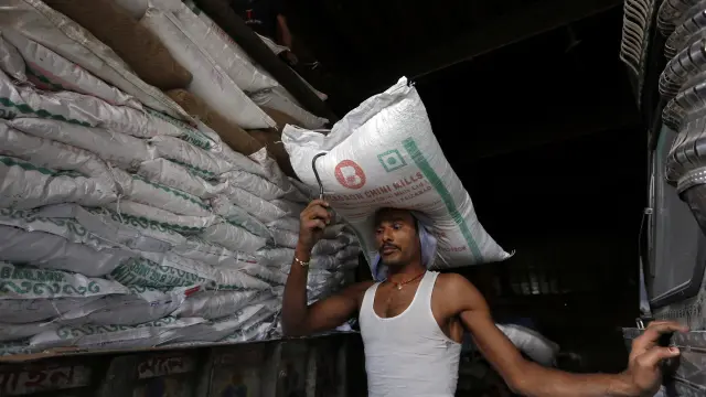 FILE PHOTO: A labourer carries a sack of sugar to load it onto a supply truck at a market area in Kolkata