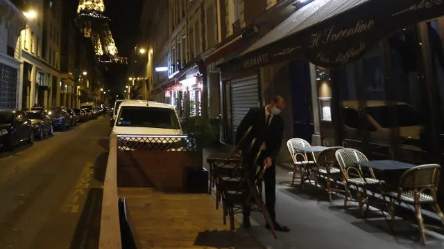 Un camarero retira las mesas de la terraza de un bar en París.