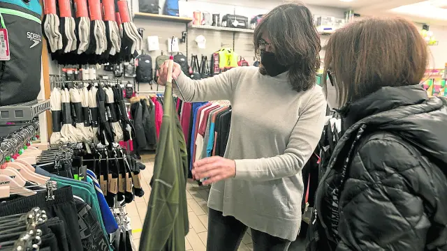 Gemma Cajal, de Intersport Huesca, enseña una prenda a una cliente en su tienda.