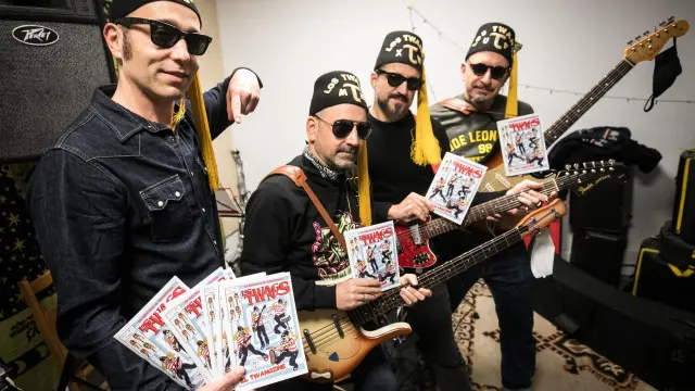 Los integrantes de Los Twangs posan con su cómic en su local de ensayo en Zaragoza.