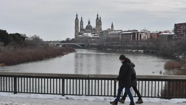 Una pareja camina entre la nieve del puente de Santiago.