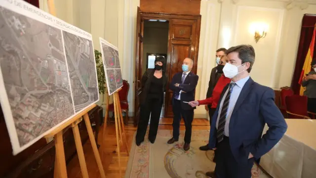 El alcalde de Huesca, en primer término, contempla los paneles donde se define la superficie y la ubicación del suelo cedido para el centro de emergencias y seguridad ciudadana.