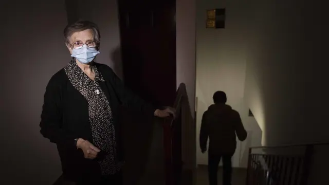 Ofelia Gracia, en la escalera de su edificio, solo iluminada por el móvil de su sobrino Carlos, que baja las escaleras.