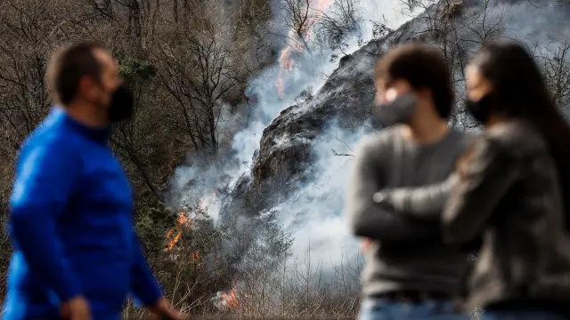 Varias personas observan este domingo en Endarlatsa (Guipúzcoa) un foco del incendio forestal.