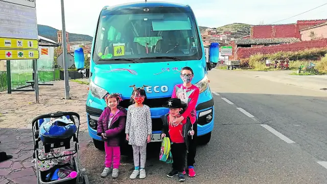 Los tres escolares de Trasobares, junto a la niña de Calcena, al lado del autobús en el que viajan.