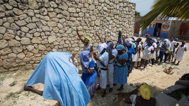 Fieles rezan a la entrada de la iglesia a la que pertenecían los 12 religiosos secuestrados el pasado fin de semana en Haití.