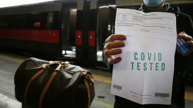 Un pasajero muestra su certificado antes de subir al tren